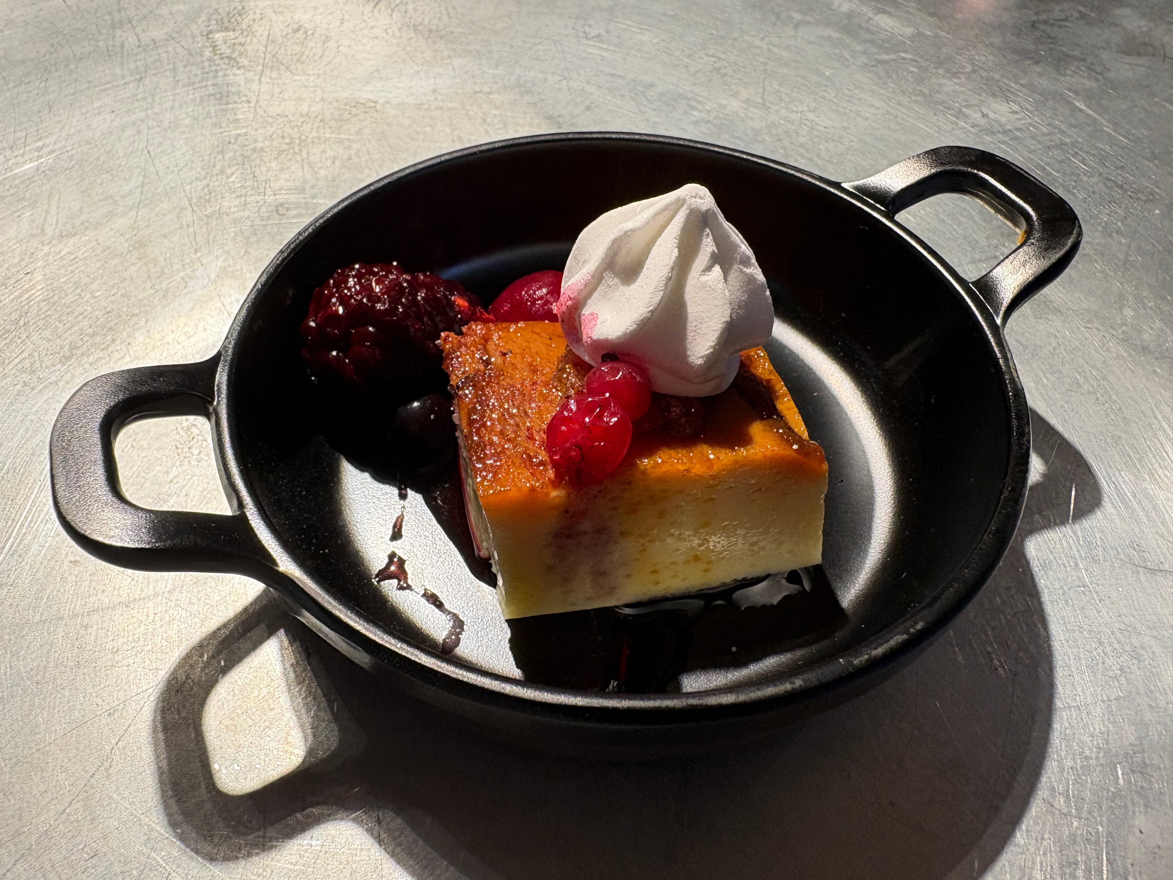 En efterrätt med bär och maräng i en liten svart panna