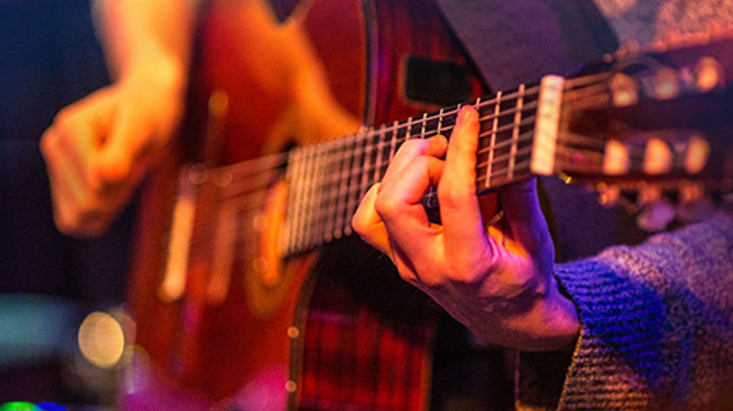 Närbild på en hand som tar ackord på en gitarrr