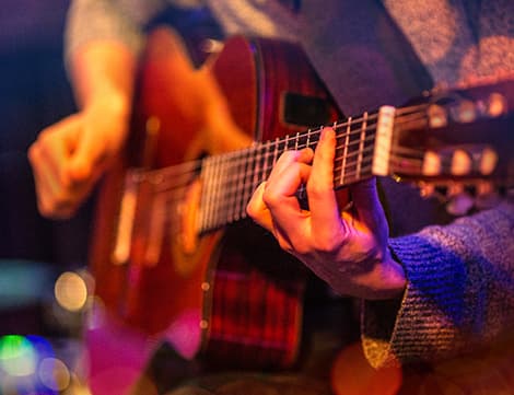 Närbild på en hand som tar ackord på en gitarrr